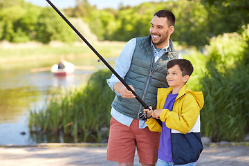 Image showing happy smiling father and son fishing on river