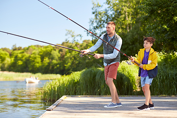 Image showing happy smiling father and son fishing on river