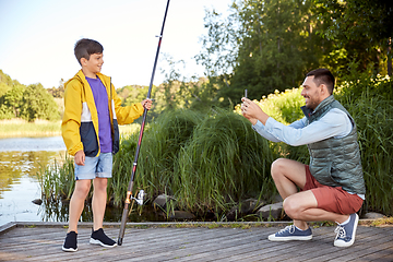 Image showing father photographing son with fishing rod on river