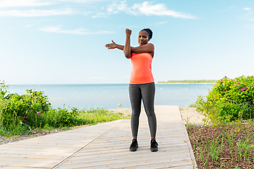 Image showing young african american woman stretching on beach