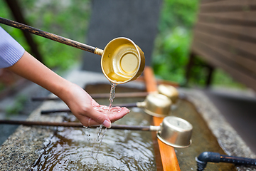 Image showing Woman washes her hand in fountain of Japanese temple