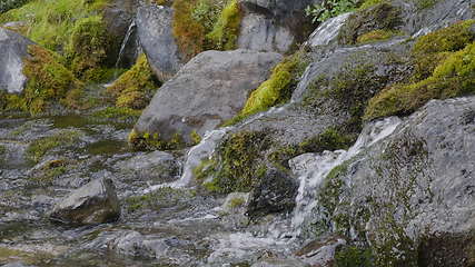 Image showing Big beautiful waterfall flows down the rocks mountains