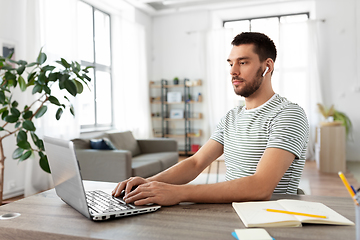 Image showing man with laptop and earphones at home office