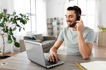 Image showing man with headset and laptop working at home