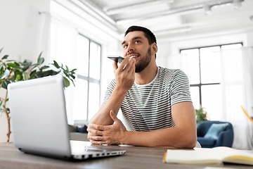 Image showing man with laptop calling on phone at home office