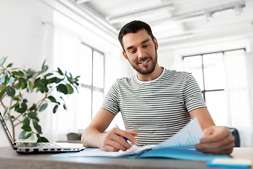 Image showing man with papers and laptop working at home office