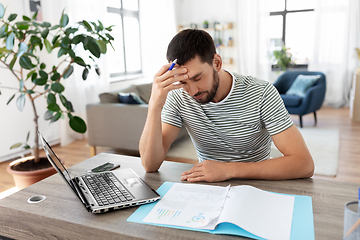 Image showing man with papers and laptop working at home office