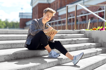 Image showing young man with notebook or sketchbook in city