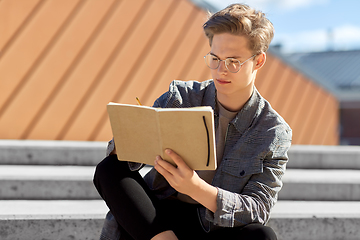 Image showing young man with notebook or sketchbook in city