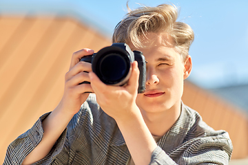 Image showing young man with camera photographing outdoors