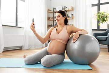 Image showing pregnant woman with smartphone and fitball at home