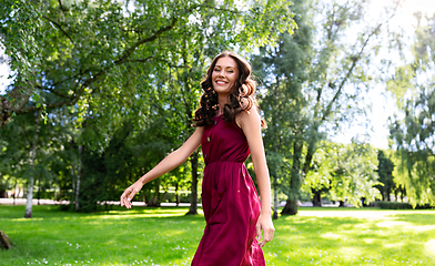 Image showing happy smiling woman walking along summer park