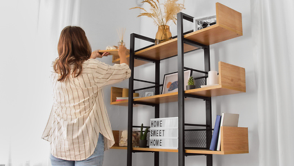 Image showing woman placing aroma reed diffuser to shelf home