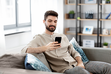 Image showing man in earphones listening to music on smartphone