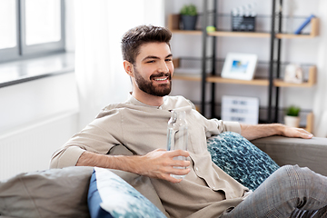 Image showing happy man drinking water from glass bottle at home