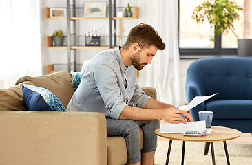 Image showing man with bills counting on calculator at home