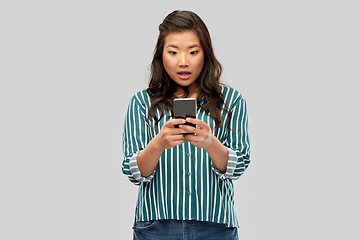 Image showing surprised asian woman using smartphone