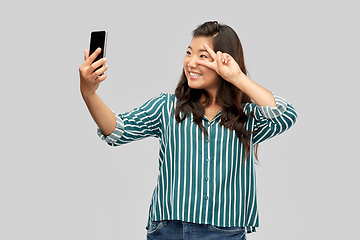 Image showing smiling asian woman taking selfie by smartphone