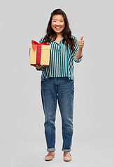 Image showing happy asian woman with gift box showing thumbs up