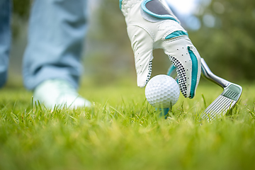 Image showing Hand in glove placing golf ball on tee