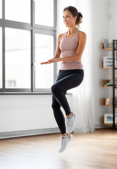 Image showing smiling young woman exercising at home