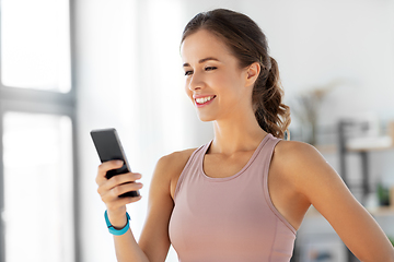 Image showing happy woman with smatphone exercising at home