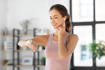 Image showing woman with smart watch and earphones doing sports