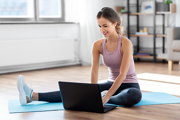 Image showing woman with laptop computer doing sports at home