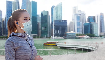 Image showing woman in mask with earphones over singapore city