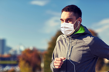 Image showing man in mask with earphones running in city