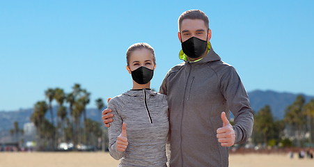 Image showing couple in masks and sportswear showing thumbs up