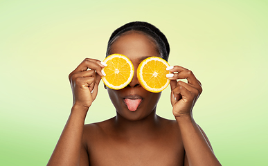 Image showing african woman making eye mask of oranges