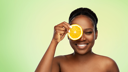 Image showing smiling african woman making eye mask of oranges