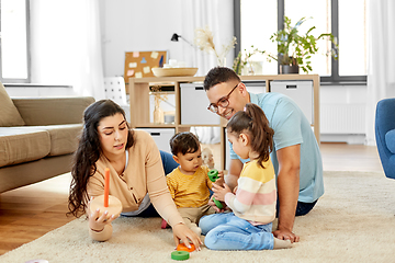 Image showing happy family playing with pyramid toy at home