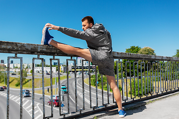 Image showing man stretching leg on bridge