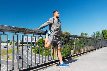 Image showing man stretching leg on bridge