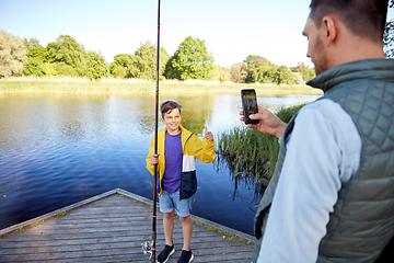 Image showing father photographing son with fishing rod on river