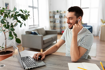 Image showing man with laptop and earphones at home office