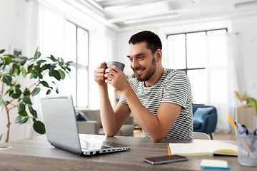 Image showing man with laptop drinking coffee at home office