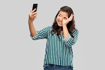 Image showing smiling asian woman taking selfie by smartphone