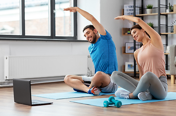 Image showing happy couple with laptop exercising at home