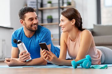 Image showing happy couple with smartphone after sports at home