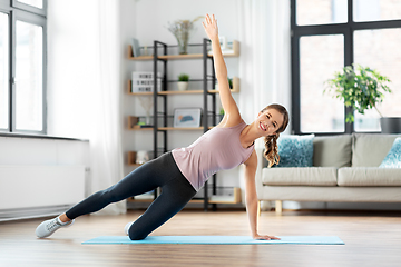 Image showing happy woman doing plank exercise on mat at home