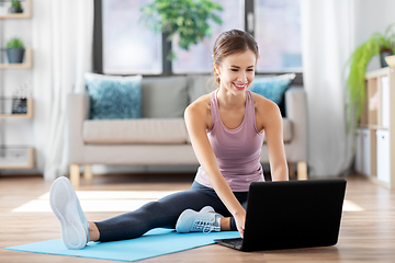 Image showing woman with laptop computer doing sports at home