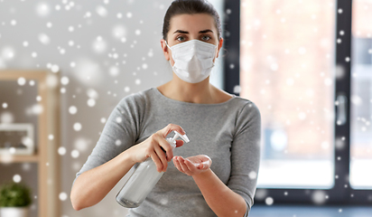 Image showing close up of woman in mask applying hand sanitizer