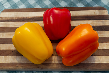 Image showing Three Colored Bell Peppers on a Wood Cutting Board
