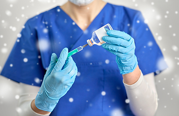 Image showing doctor in face mask with syringe and medicine