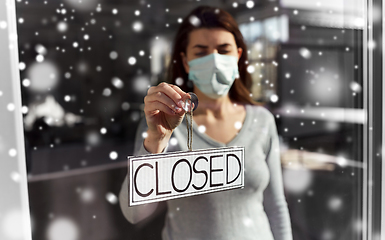 Image showing woman in mask hanging banner closed on door