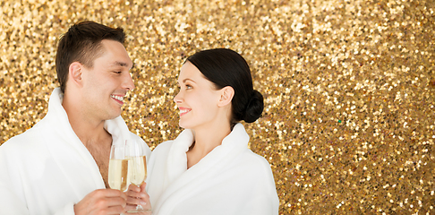 Image showing happy couple in spa bath robes drinking champagne