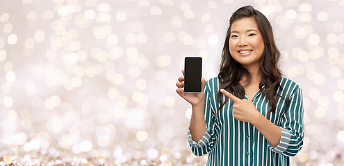 Image showing happy asian woman with smartphone over lights